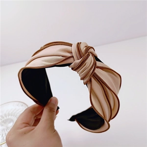 Close-up of beige knotted headband with dark brown piping and soft matte silk texture