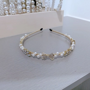 Close-up of golden metal headband with white pearls and sparkling rhinestone butterfly