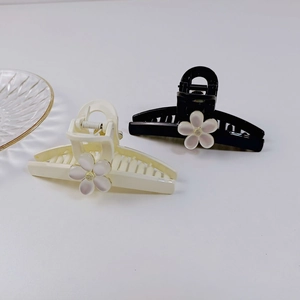 Détail de pinces à cheveux noires et crème avec fleurs perlées et accents dorés