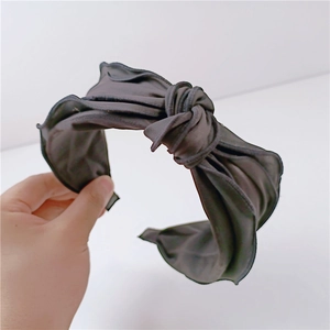 Detail view of the soft black fabric texture and twisted knot bow on the wide headband