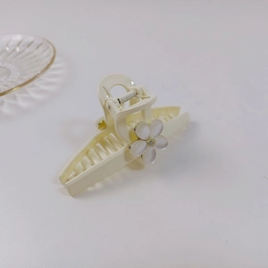 Détail d'une pince à cheveux fleur blanc crème avec pétales nacrés et cœur doré élégant