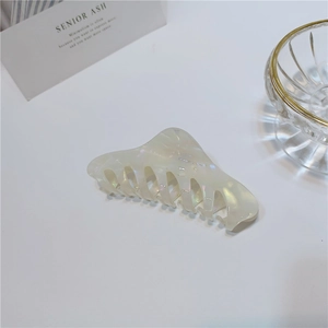 Detailed close-up of a large pearlescent acetate hair claw clip on a white minimalist desk