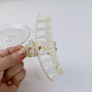 Détail de la pince à cheveux en résine crème avec fleur de perle et ressort métallique