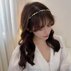 Elegant gold headband with white flowers and crystals worn by a model with long curly hair