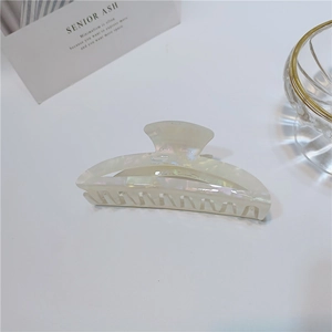 Detail of large acetate hair claw clip with pearlescent mermaid finish on desk