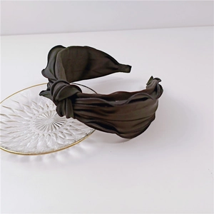 Detailed view of a wide black knotted headband featuring elegant pleats and satin texture