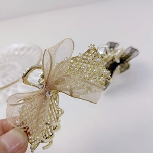 Pince à cheveux dorée avec nœud en organza beige et détails de perles blanches