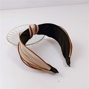 Detail of a two-tone wide headband with knot design in beige and black satin fabric