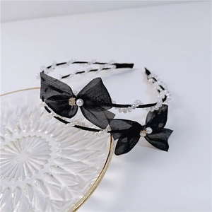 Elegant double-layer black headband with mesh bows and white pearls on a glass tray