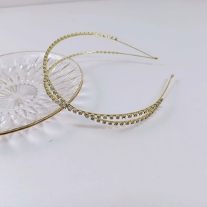 Cerchietto minimalista dorato a doppio strato con strass scintillanti su vassoio in vetro
