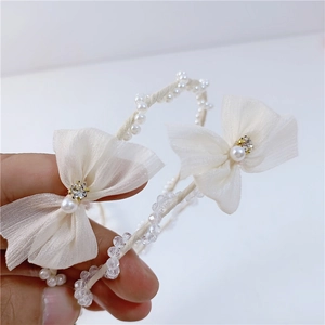 Detailed shot of mesh bow hairband featuring elegant white lace with sparkling rhinestones