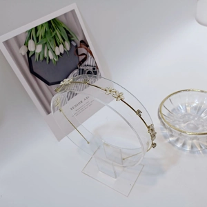 Detail view of golden floral headband with white petals and sparkling crystals on a stand