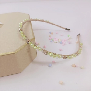 Dettaglio di un cerchietto elegante con perle e cristalli sopra una scatola regalo
