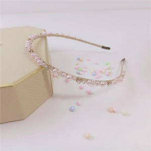 Dettaglio del cerchietto sottile con perle rosa e cristalli su portagioie elegante
