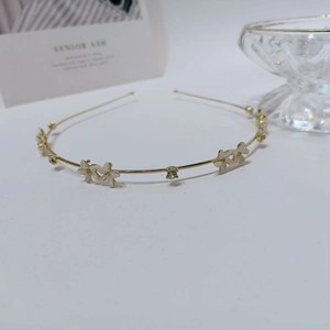 Detailed close-up of golden metal headband with white floral resin petals and crystal rhinestones
