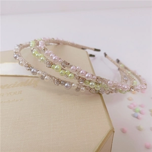 Dettaglio di tre cerchietti coreani con perle e cristalli colorati su scatola regalo