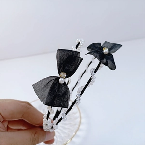 Detail of thin crystal headband with black mesh bow and pearls held by hand
