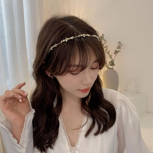 Elegant gold metal headband with white enamel flowers and crystals worn by a model
