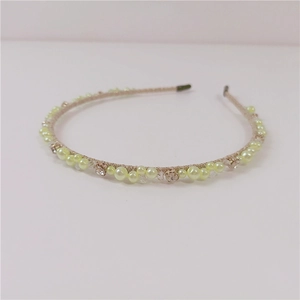 Dettaglio di strass champagne e perle giallo chiaro sulla fascia per capelli in tessuto