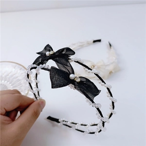 Detailed view of mesh bow hairband and pearl headband set with crystal accents
