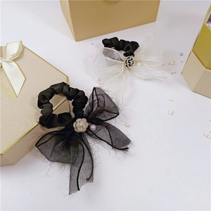 Détail de chouchous élégants en tulle avec fleur de camélia et perles pendantes