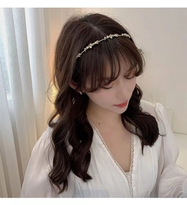 Elegant gold metal headband with white floral petals and pearl accents worn by a model