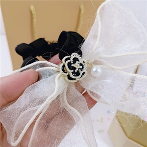 Détail d'un chouchou en dentelle avec fleur de camélia, perles blanches et ruban