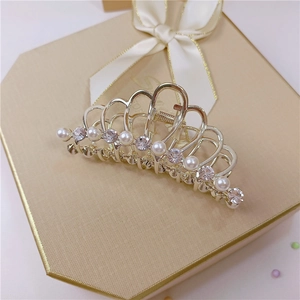 Dettaglio di un fermaglio a corona dorata con perle su una confezione regalo di lusso