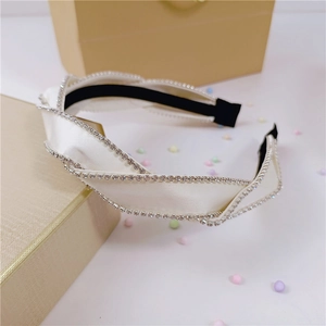 Detail view of the white satin headband featuring shiny rhinestones and twist knot design