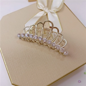 Dettaglio molletta a corona dorata con strass rosa su elegante scatola regalo