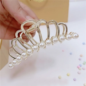 Dettaglio di un fermaglio per capelli in metallo dorato con eleganti perle bianche