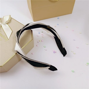 Close-up of black and white twisted headband with sparkling rhinestones and gift box