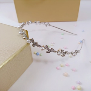 Detailed view of silver leaf headband with white pearls on a decorative gift box