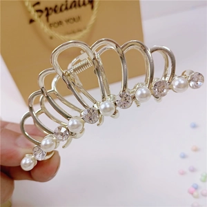 Dettaglio ravvicinato di una molletta a corona dorata con perle e strass