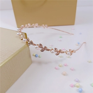 Detailed view of golden leaf headband with white faux pearls on a gift box