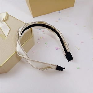 Close-up of sparkling rhinestone headband with creamy white twisted fabric and soft tips