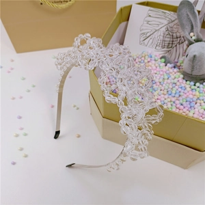 Détail d'un serre-tête fleuri en cristal artisanal sur une boîte cadeau dorée
