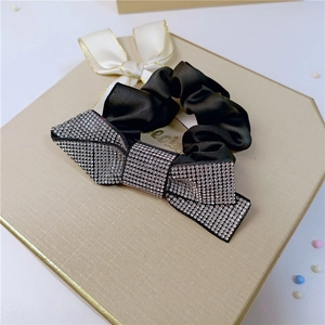 Elegant black satin scrunchie with a large sparkling rhinestone bow on a gift box