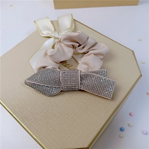 Elegant champagne crystal bow scrunchie with cream satin fabric and gold trim detail