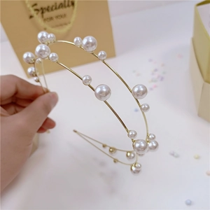 Dettaglio di un elegante cerchietto dorato a doppio strato con perle bianche