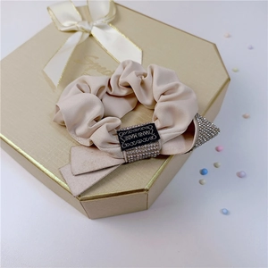 Detail of silk hair scrunchie with rhinestones and Hand Made tag on golden gift box