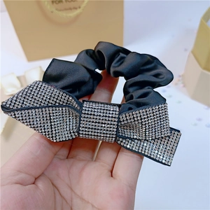 Macro detail of black satin scrunchie with sparkling rhinestone bow tie accessory