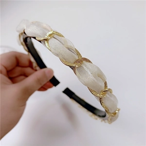 Detail view of the twisted gold chain and cream pleated fabric on the resin headband