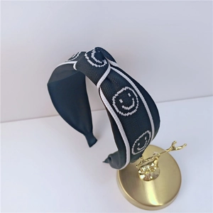 Serre-tête en tricot noir avec motif smiley blanc et détail de nœud croisé chic