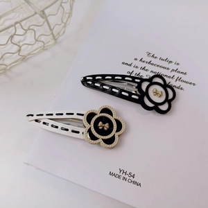 Detail of floral hair clips featuring leather trim and golden bow charm accents