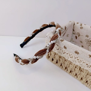 Detailed close-up of a brown velvet braid headband with pearls and rhinestones