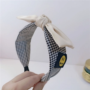 Détail d'un serre-tête en tissu à carreaux noirs et blancs avec nœud crème élégant