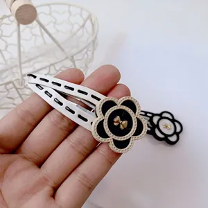 Handheld elegant black and white leather flower hair clip with a golden bow accent
