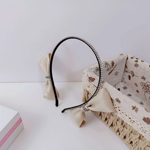 Elegant headband with champagne satin bows and sparkling silver rhinestones on slim black frame