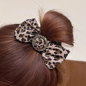 Leopard print bow hair scrunchie with rhinestone ring worn on a stylish hair bun